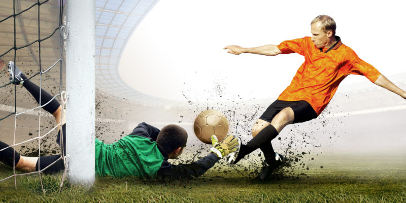 Shoot of football player and jump of goalkeeper on the field of